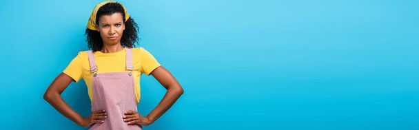 незадоволена афроамериканська жінка, що стоїть з руками на стегнах на синьому, банер
 - Фото, зображення