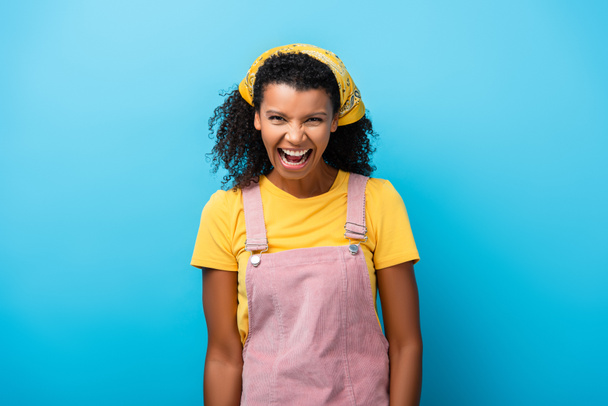 africký americký žena s otevřenými ústy smích na modrý  - Fotografie, Obrázek