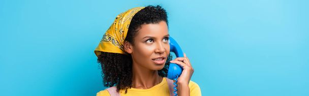 青旗でレトロな電話で話すアフリカ系アメリカ人女性 - 写真・画像