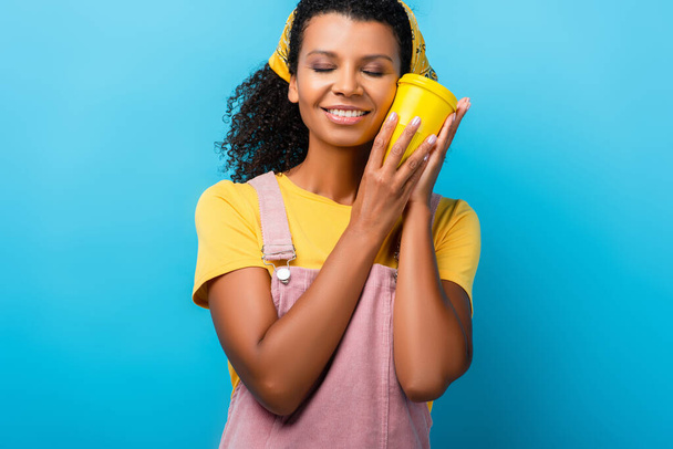 boldog afro-amerikai nő csukott szemmel, kezében újrahasznosítható bögre kék - Fotó, kép