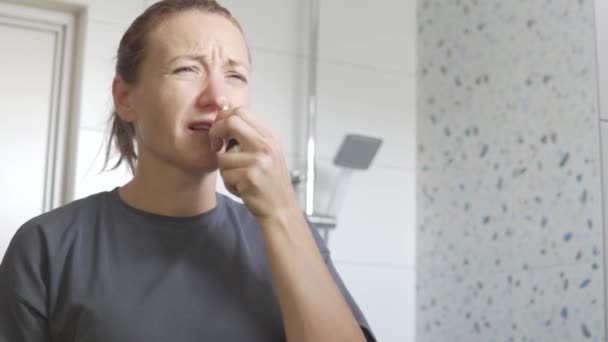 Una donna getta gocce nel naso della casa davanti allo specchio. - Filmati, video