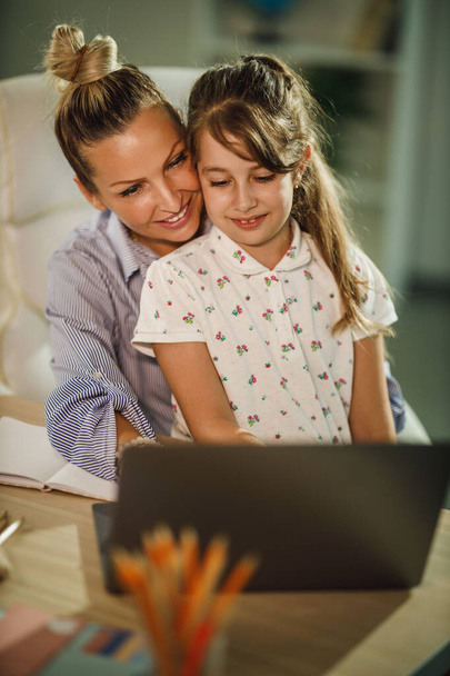 Съемка милой маленькой девочки и ее прекрасной молодой матери с ноутбука во время видео-звонка во время пандемии COVID-19. - Фото, изображение