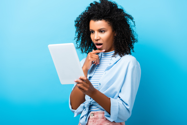 chocado afro-americano mulher usando tablet digital em azul  - Foto, Imagem