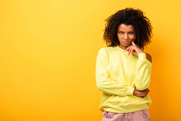 serious african american woman looking at camera on yellow - 写真・画像