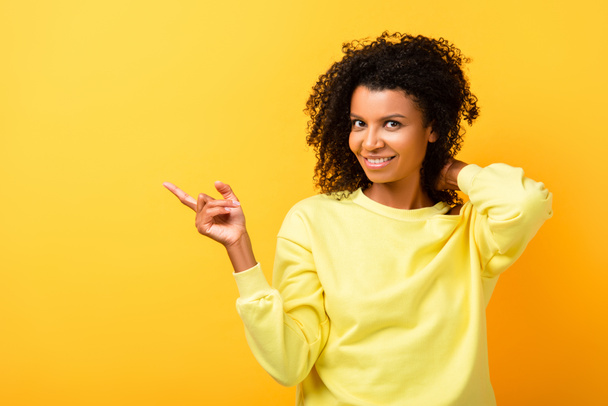 happy african american woman pointing with finger on yellow - Photo, Image