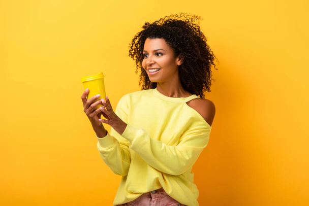 cheerful african american woman holding reusable eco cup on yellow - Foto, Imagem