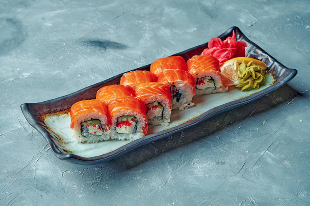 Japanese sushi roll philadelphia with cream cheese, salmon and tobiko caviar in a white plate on a gray background - Foto, immagini