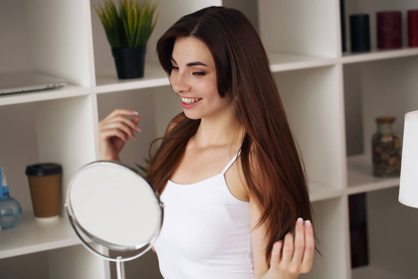 鏡の前の家で滑らかな肌に触れる美しい女性 - 写真・画像