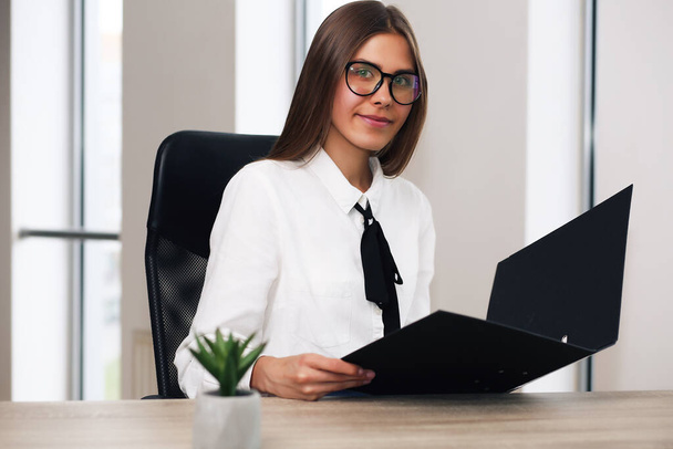 young business lady sitting in a chair working, holding a folder with documents - Photo, Image