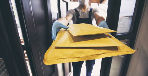 The delivery man handing the parcel to the customer at his home - Foto, imagen