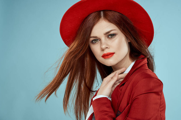 美しいです女性で赤い帽子ジャケット赤い唇長い髪の魅力青の背景 - 写真・画像