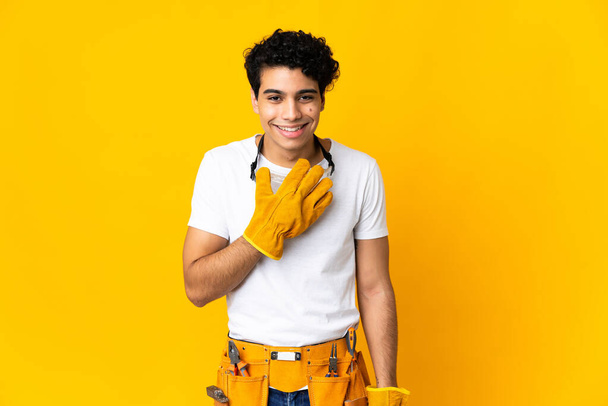 Venezuelan electrician man isolated on yellow background happy and smiling covering mouth with hand - Fotografie, Obrázek