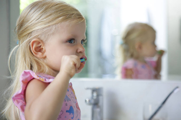 Adorable 3 years old girl brushing her teeth in bathroom. - Foto, imagen