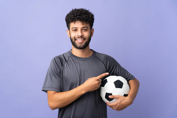 Przystojny Marokański młody piłkarz człowiek na izolowane na fioletowym tle wskazując na stronie przedstawić produkt - Zdjęcie, obraz