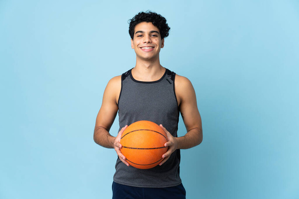 Young Venezuelan man isolated on blue background playing basketball - Foto, afbeelding