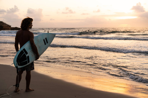 Young caucasian man get up early to  doing surf at sunrise - Photo, Image