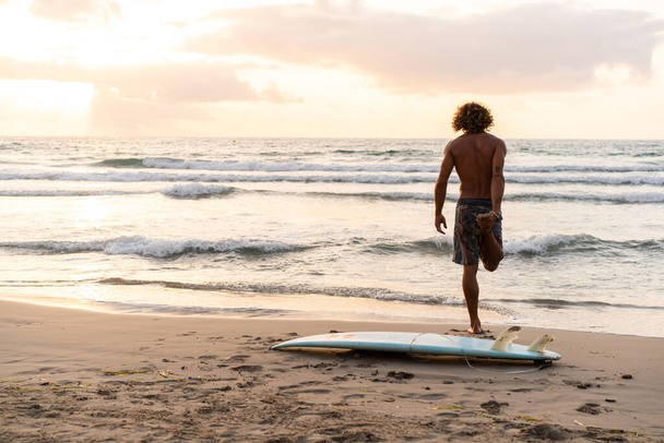 Jeune homme caucasien se lever tôt pour faire du surf au lever du soleil - Photo, image