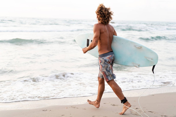 Joven caucásico hombre levantarse temprano a hacer surf al amanecer - Foto, imagen