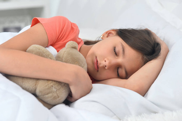 Cute little girl sleeping in bed with teddy bear  - Foto, imagen