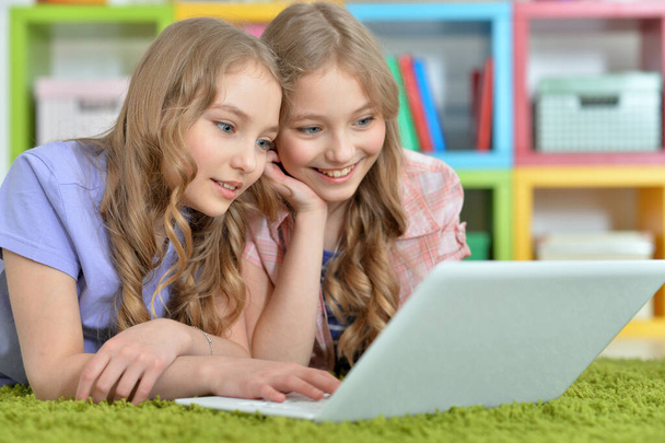 Two pretty little girls lying on floor and using laptop - Foto, immagini