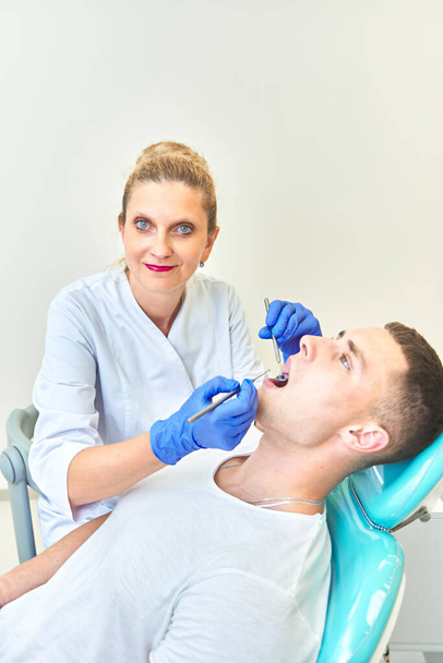 dentist doctor examines the mouth of a young guy. man at the stomatologist - Photo, image