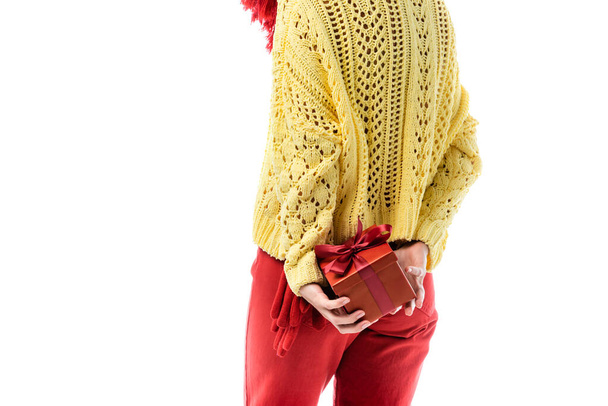 cropped view of young woman in knitted sweater holding present behind back isolated on white - Photo, image