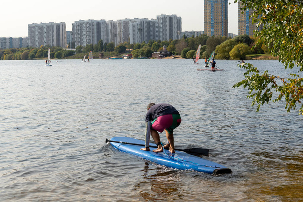 Standup paddleboarding są na rzece Moskwie, Strogino. Koncepcja zdrowego stylu życia. - Zdjęcie, obraz