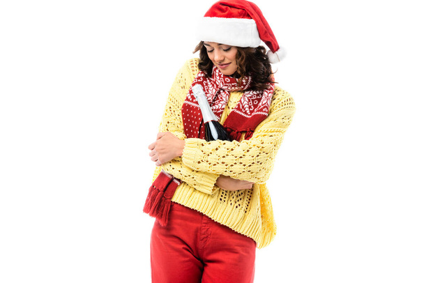 giovane donna in cappello di Babbo Natale e sciarpa con ornamento in possesso di bottiglia di champagne isolato su bianco  - Foto, immagini