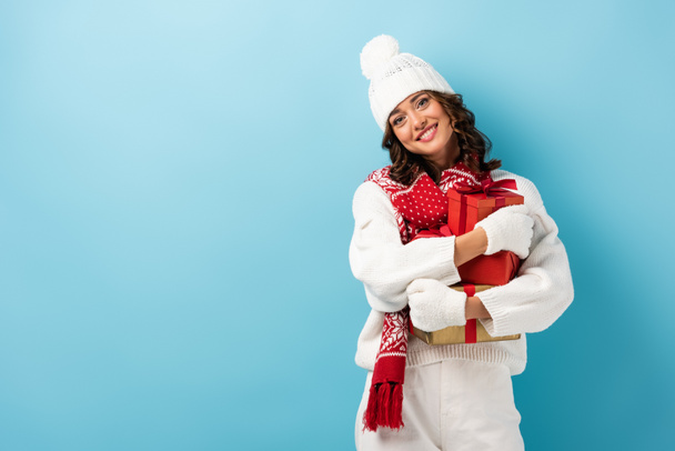 jeune femme heureuse en tenue d'hiver blanche exploitation présente sur bleu - Photo, image
