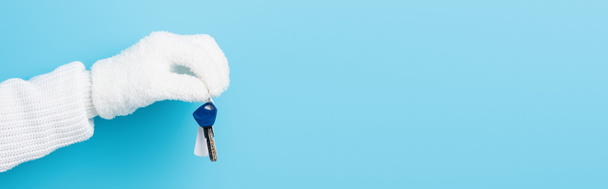 panoramic crop of woman in white glove holding key on blue - Foto, afbeelding