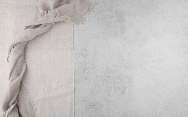 Pure washed linen cloth and tablecloth on light grunge stone background. Natural washed linen fabric on stone tile surface with copy space - Zdjęcie, obraz