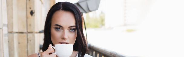 schöne brünette Frau trinkt Kaffee auf Balkon, horizontales Banner - Foto, Bild