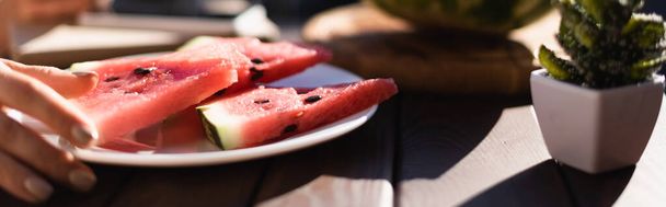 plate with watermelon slices on foreground and female hand, horizontal banner - Photo, Image