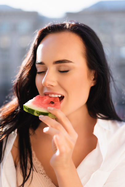 portrait of brunette woman eating watermelon with closed eyes - Foto, afbeelding