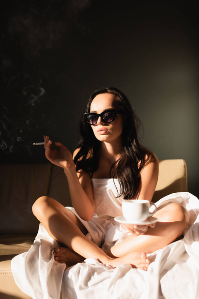sexy brune femme couverte de blanc feuille fumer cigarette et boire du café - Photo, image
