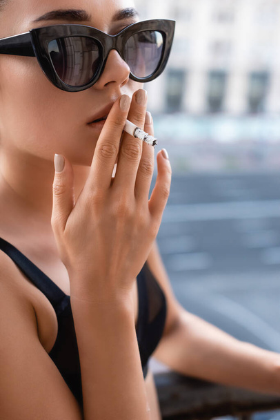 sexy joven mujer en negro ropa interior fumar cigarrillo en balcón - Foto, imagen