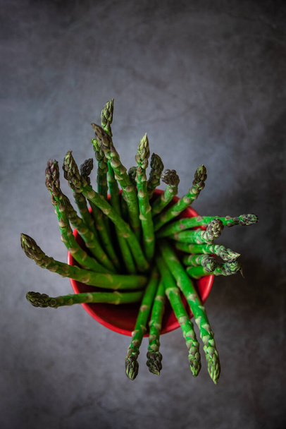 Green fresh asparagus on black slate stone background. Top view. - 写真・画像