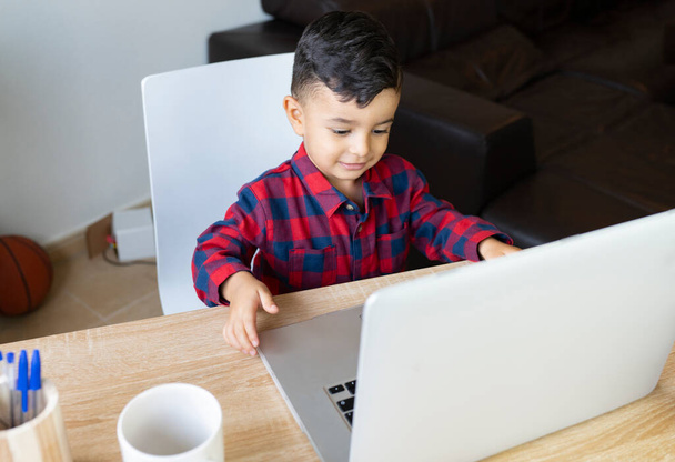 ein Kind, das zu Hause mit dem Online-Computer Hausaufgaben macht, - Foto, Bild