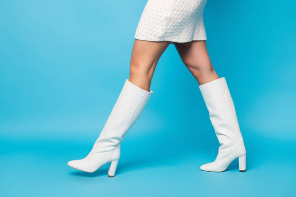 Cropped profile side photo of gorgeous magnificent vogue girls legs walking going on fashion runway wear leather trend boots isolated over blue color background - 写真・画像