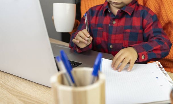 bambino con sua madre fa i compiti a casa con il computer portatile - Foto, immagini