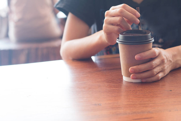 Eine Frau hält mittags eine Kaffeetasse im Kaffeehaus. - Foto, Bild