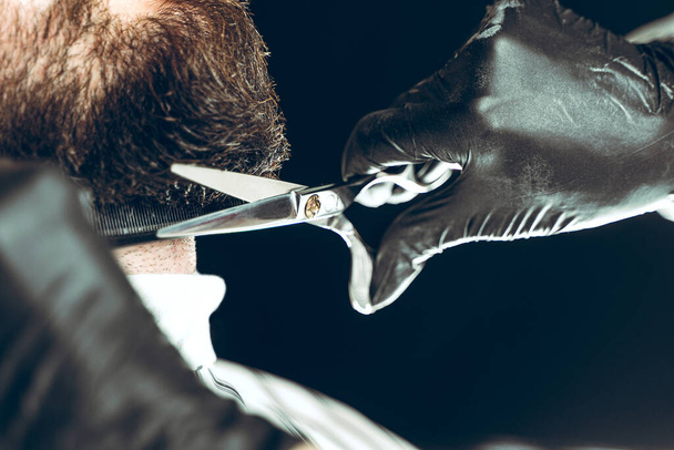 Visit to the barbershop. The master makes a beard cut with scissors - Photo, Image