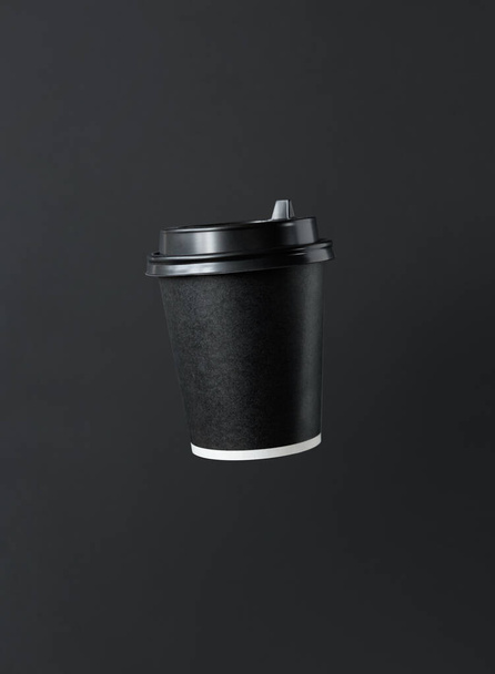 Fliegende Kaffee- oder Teepapierbecher mit Deckel auf dunklem Hintergrund. Logo-Vorlage - Foto, Bild