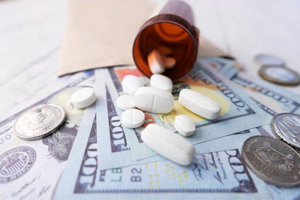 Gezondheidszorg kostenconcept met ons dollar, container en pillen op tafel  - Foto, afbeelding