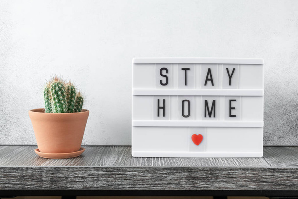 Lightbox with text STAY HOME and cactus plants on wooden table. Stay safe, stay inside home concept - Image - Zdjęcie, obraz