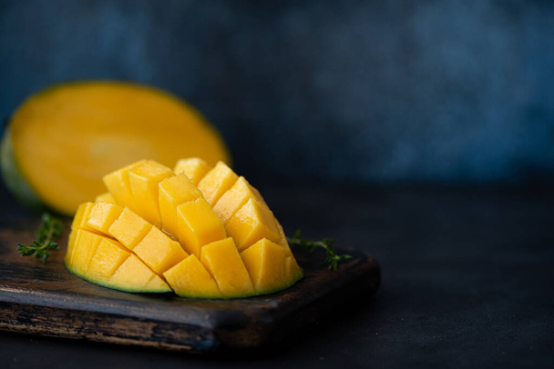 large ripe mango cut into pieces on a dark blue background - Foto, Imagen