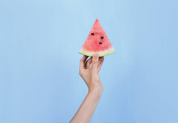 Hand holding slice of ripe watermelon on blue background - Fotografie, Obrázek