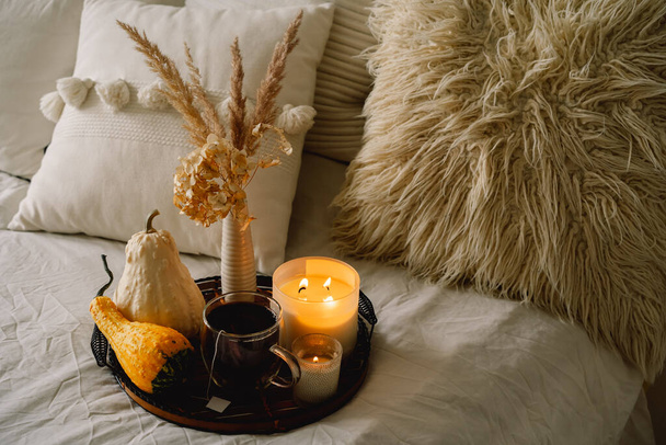Stillleben Details im heimischen Wohnzimmer. Kürbis und Tasse Tee mit Kerzen auf einem Serviertablett. - Foto, Bild