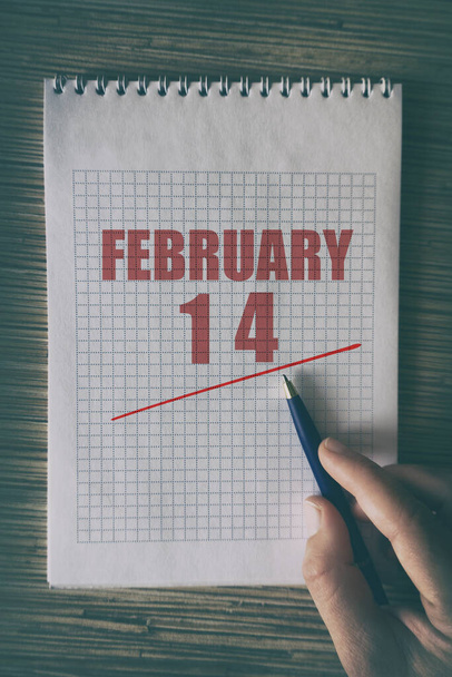 14 лютого. 14 день місяця, крупним планом людська рука з ручкою на блокноті з червоною підкресленою датою. зимовий місяць, день року концепція
. - Фото, зображення
