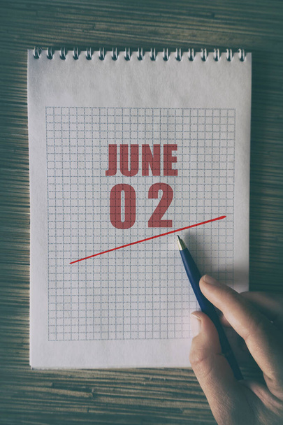 2 Ιουνίου. Ημέρα 2 του μήνα, Κοντινό πλάνο του ανθρώπινου χεριού με στυλό στο σημειωματάριο με κόκκινο υπογράμμισε ημερομηνία. καλοκαίρι μήνα, ημέρα του έτους έννοια. - Φωτογραφία, εικόνα
